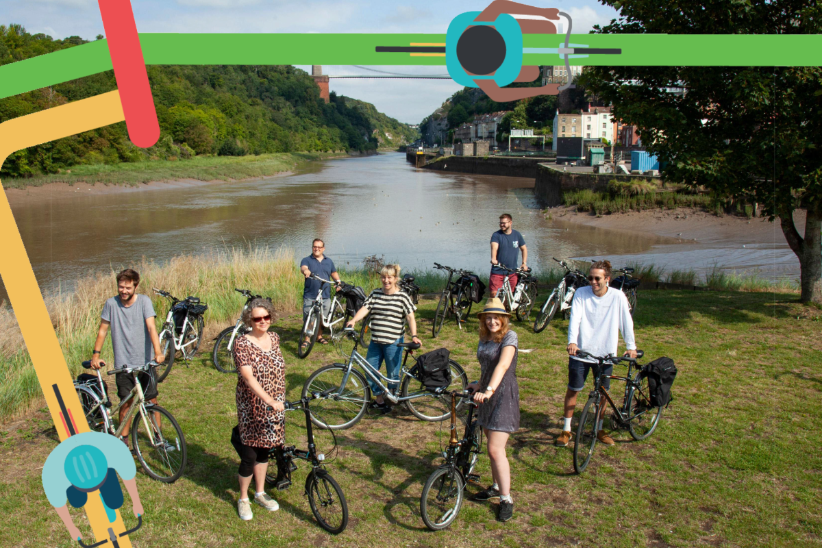 A group of people stood in front of the suspension bridge with bicycles.