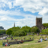 a city scape with people relaxing in a park on a sunny day