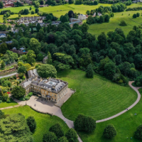 An arial view of a large green estate with a stately home in centre
