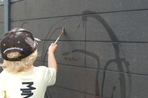 A young child paints on a black wall with water.