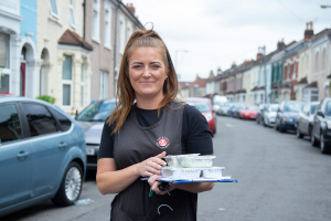 Community meals employee standing in street holding a meal