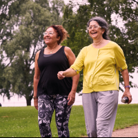 Two women in activewear walking in a park.