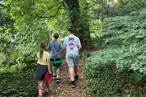 Three kids walking along a path in a wood.